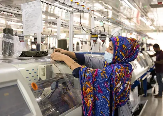 Female operator running flat-bed knitting machine at a Bangladesh knitwear factory — Next Apparels sourcing partner