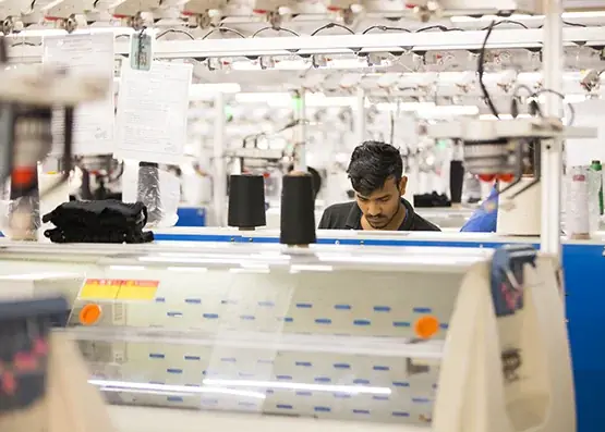 Technician programming knitting machine at a Bangladesh sweater manufacturer